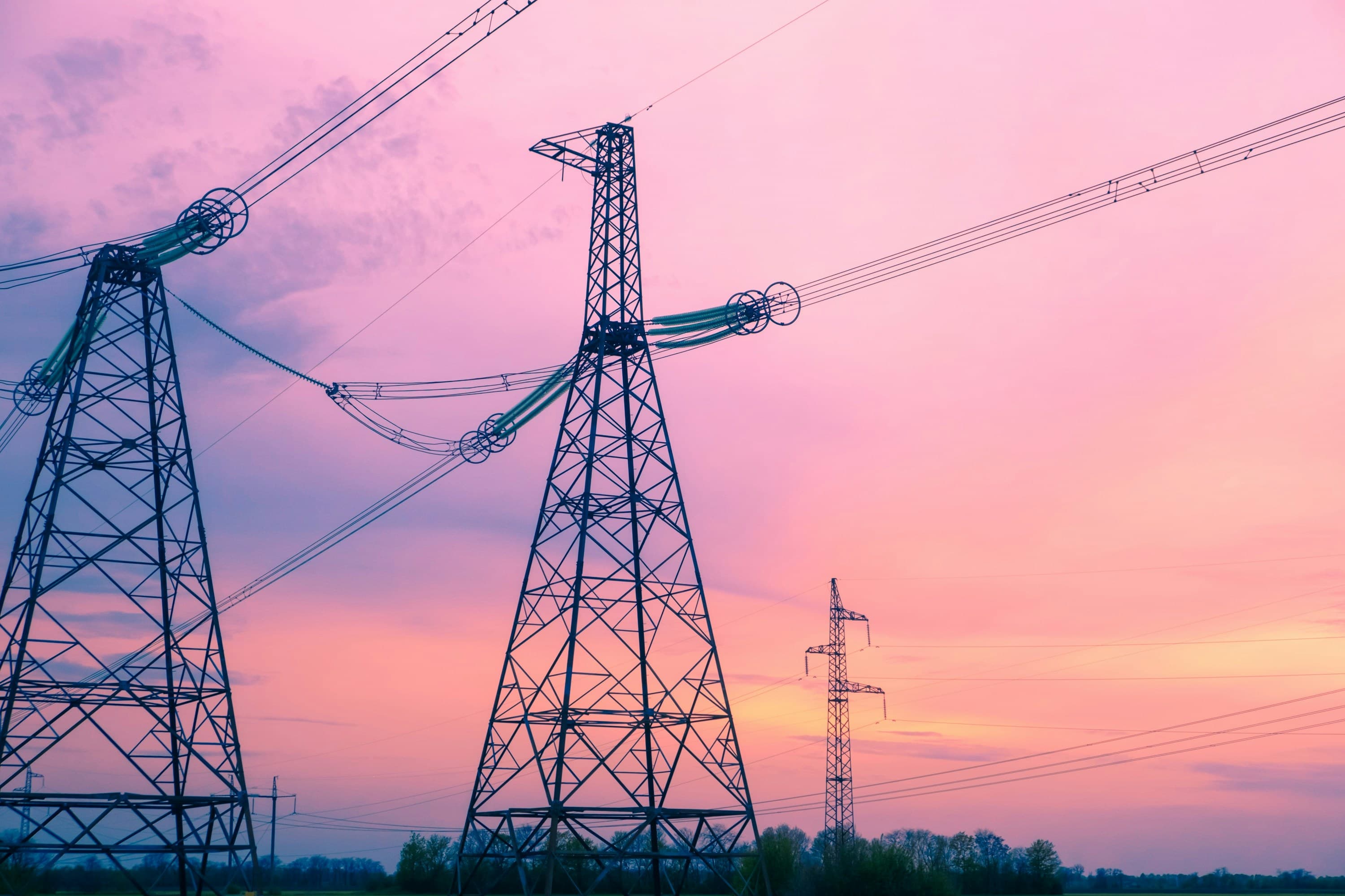 Electrical transmission towers at sunset with pink and orange sky